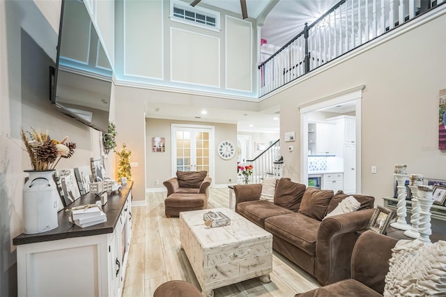 living room with light hardwood / wood-style floors and a towering ceiling