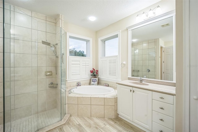 bathroom featuring a textured ceiling, vanity, and shower with separate bathtub