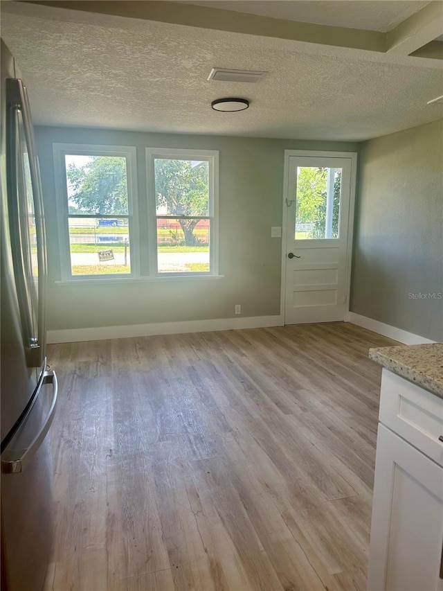 entryway featuring a textured ceiling, plenty of natural light, light wood-style flooring, and baseboards