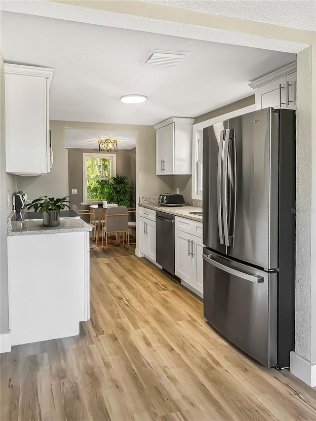 kitchen with white cabinetry, freestanding refrigerator, light wood finished floors, dishwasher, and light countertops