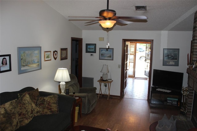 living room featuring ceiling fan, dark hardwood / wood-style floors, a fireplace, a textured ceiling, and lofted ceiling