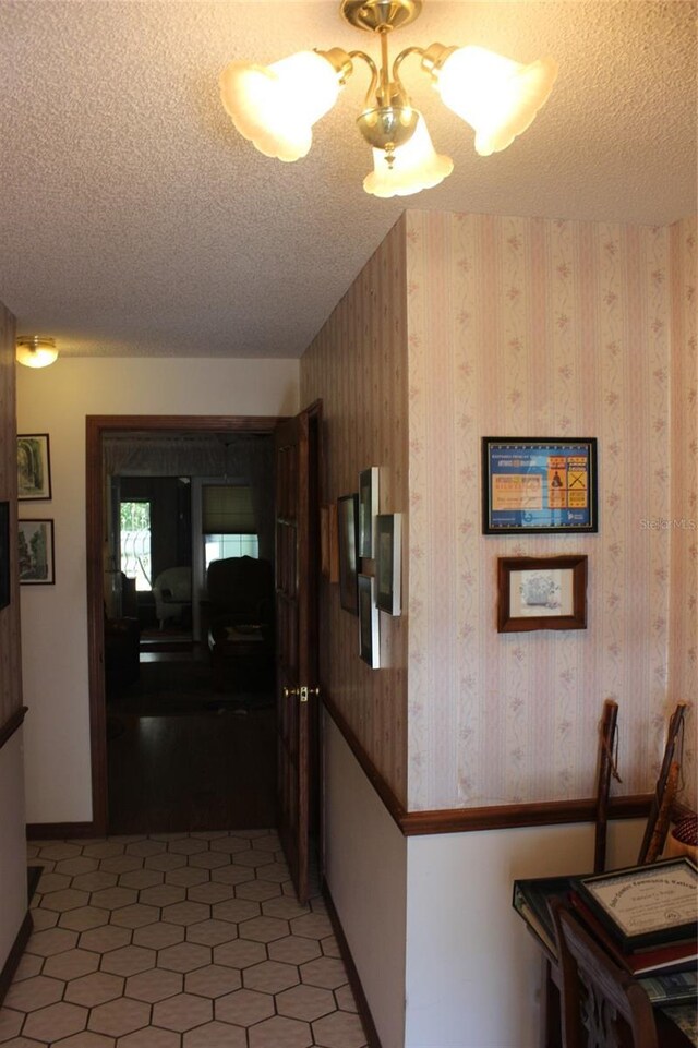 hall featuring tile patterned flooring, a textured ceiling, and wooden walls