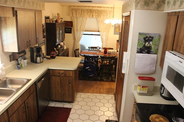 kitchen with light tile patterned floors, sink, decorative light fixtures, and dishwashing machine