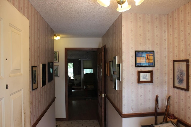 hall with a textured ceiling and tile patterned floors