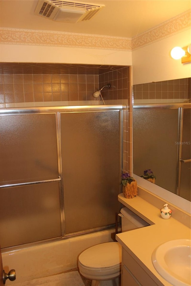 full bathroom with combined bath / shower with glass door, vanity, and toilet