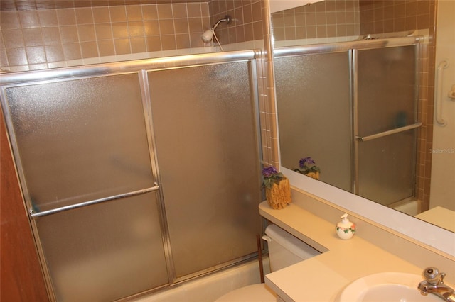 full bathroom with enclosed tub / shower combo, vanity, and toilet