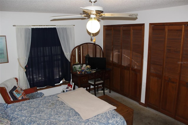 carpeted bedroom with a textured ceiling, ceiling fan, and two closets