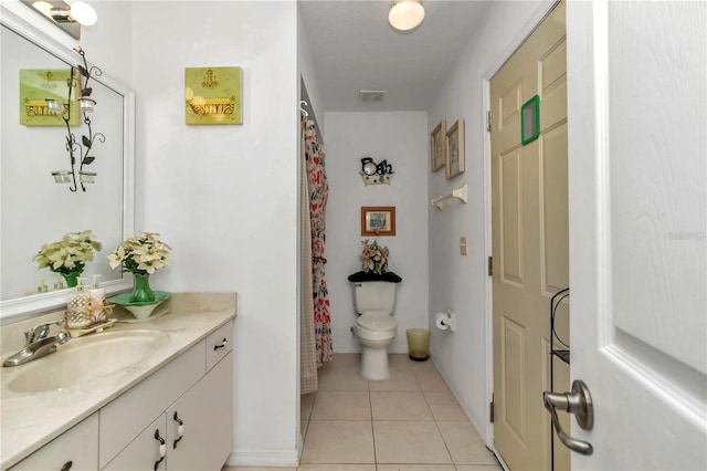 bathroom with toilet, vanity, and tile patterned floors