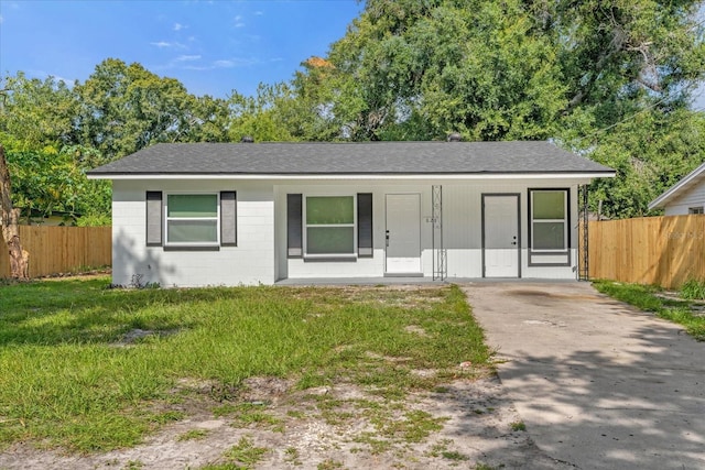 view of front of home featuring concrete block siding, fence, and roof with shingles