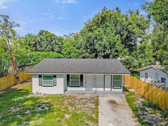 view of front of house featuring concrete driveway, fence, a front yard, and roof with shingles