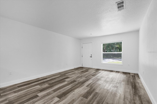 empty room featuring dark wood finished floors, baseboards, visible vents, and a textured ceiling