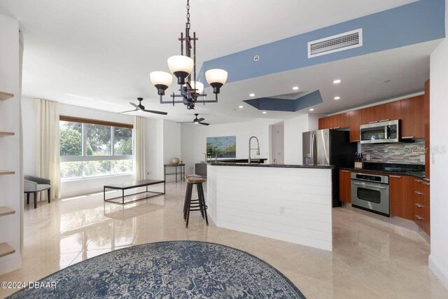 231 Riverside Dr Unit 101-1, Holly Hill, FL 32117 - kitchen with stainless steel appliances, a ceiling fan, brown cabinetry, dark countertops, and a chandelier