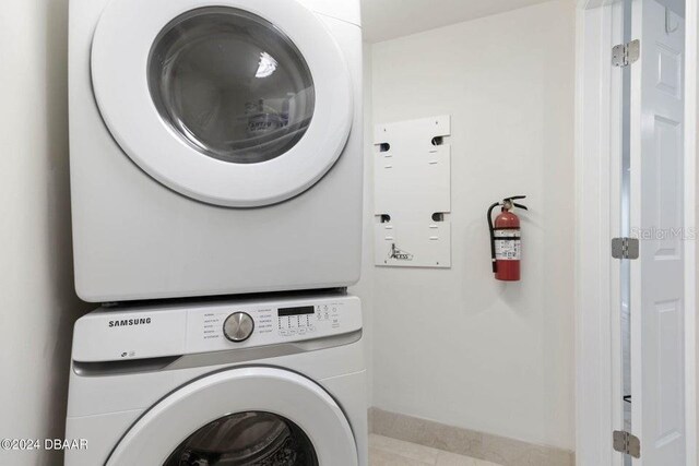 231 Riverside Dr Unit 101-1, Holly Hill, FL 32117 - laundry room featuring stacked washing machine and dryer, tile patterned flooring, and baseboards