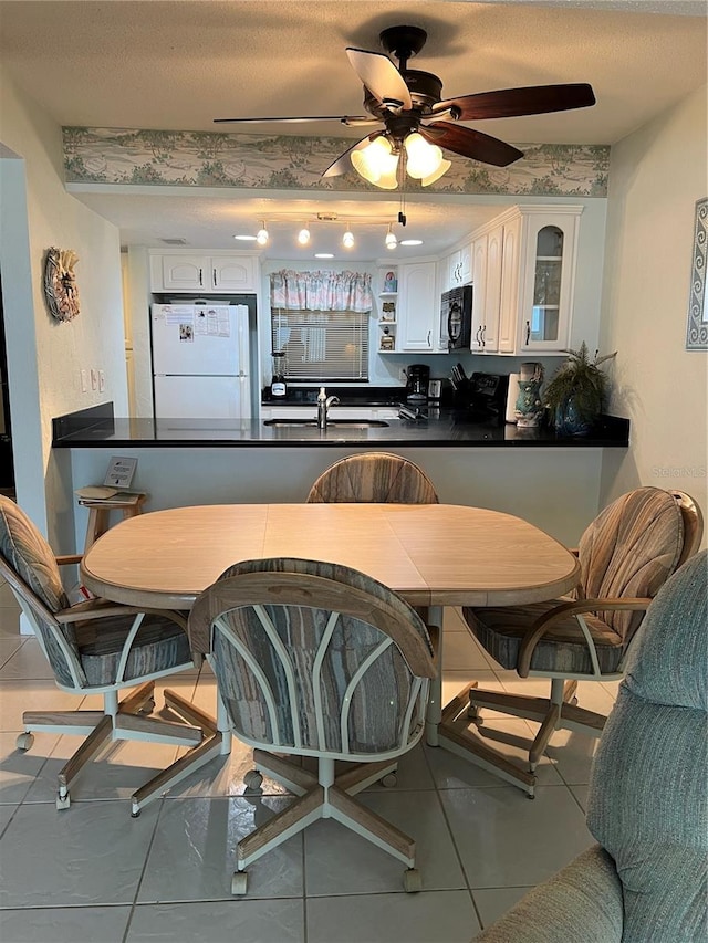 tiled dining area featuring sink, ceiling fan, and a textured ceiling