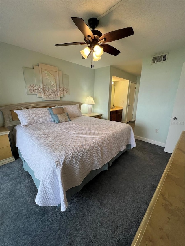 bedroom featuring ceiling fan, dark colored carpet, and ensuite bath