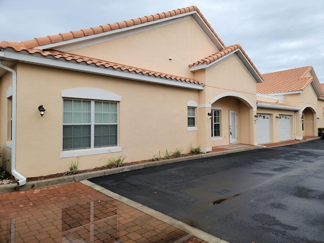 mediterranean / spanish-style house featuring a garage, a tile roof, and stucco siding