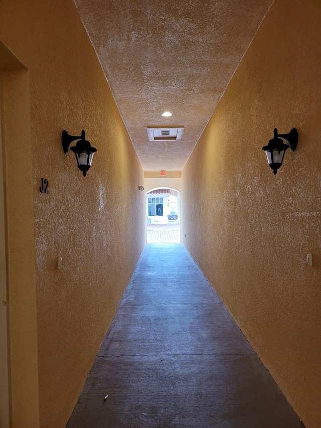 hall featuring a textured wall and visible vents