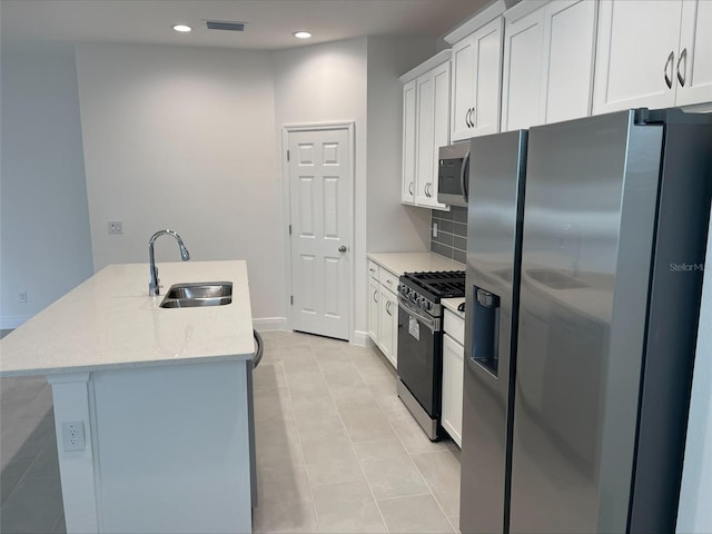 kitchen featuring stainless steel appliances, sink, white cabinets, and a kitchen island with sink