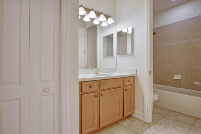 full bathroom featuring toilet, tile patterned flooring, tiled shower / bath, and vanity