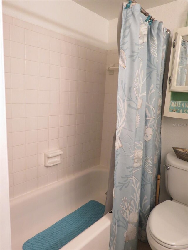 bathroom with shower / bath combo with shower curtain and toilet