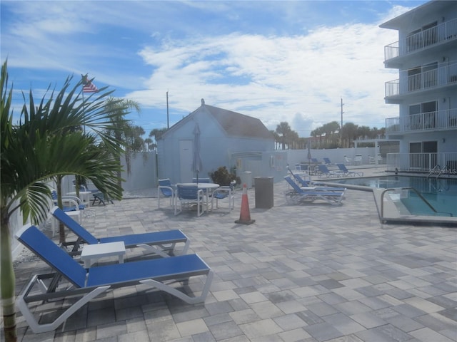 view of patio / terrace featuring an outbuilding, fence, and a community pool