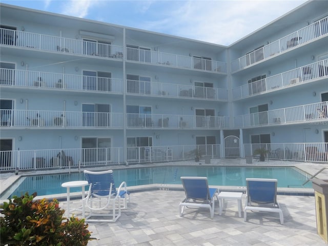 community pool with a patio area and fence