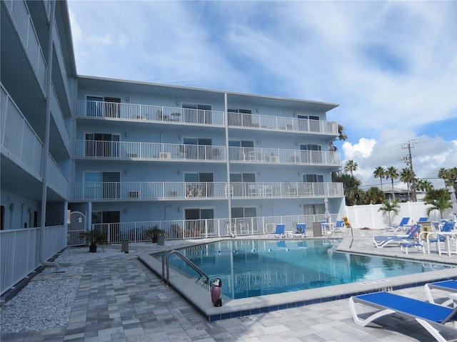 community pool with a patio area and fence