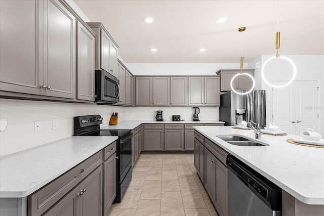 kitchen with pendant lighting, gray cabinets, an island with sink, sink, and stainless steel appliances