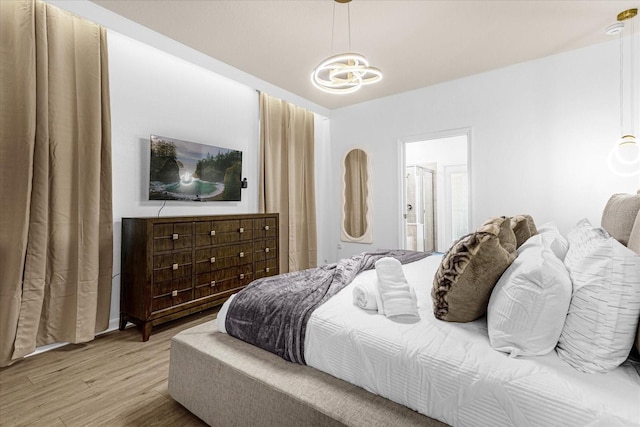 bedroom with ensuite bathroom, an inviting chandelier, and wood-type flooring