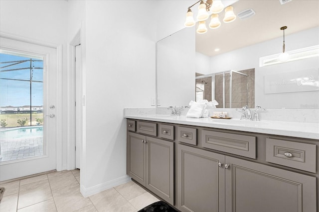 bathroom with a shower with shower door, an inviting chandelier, vanity, and tile patterned floors