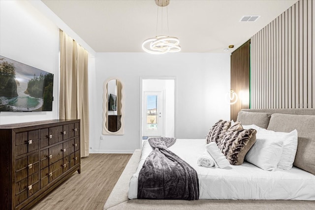 bedroom with light wood-type flooring and a chandelier