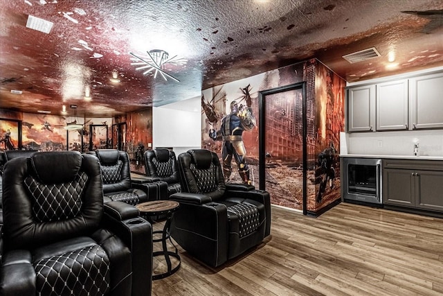 cinema with sink, hardwood / wood-style floors, a textured ceiling, and beverage cooler