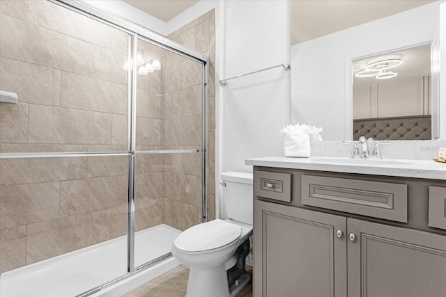 bathroom with a shower with shower door, vanity, and toilet