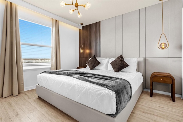 bedroom with light wood-type flooring and an inviting chandelier