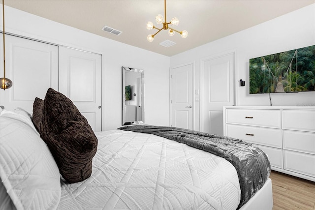 bedroom featuring a closet, light hardwood / wood-style floors, and a notable chandelier