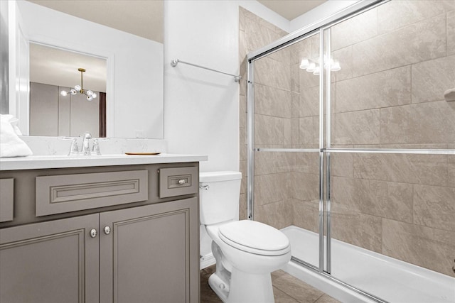 bathroom featuring toilet, vanity, tile patterned floors, a notable chandelier, and a shower with shower door