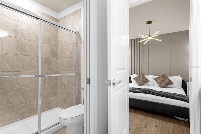 bathroom featuring wood-type flooring, a shower with shower door, an inviting chandelier, and toilet