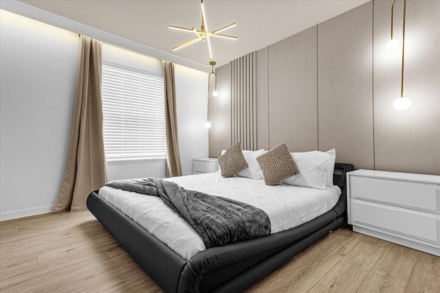 bedroom featuring an inviting chandelier and light wood-type flooring