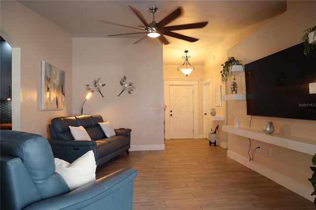 living room with light hardwood / wood-style flooring, ceiling fan, and vaulted ceiling