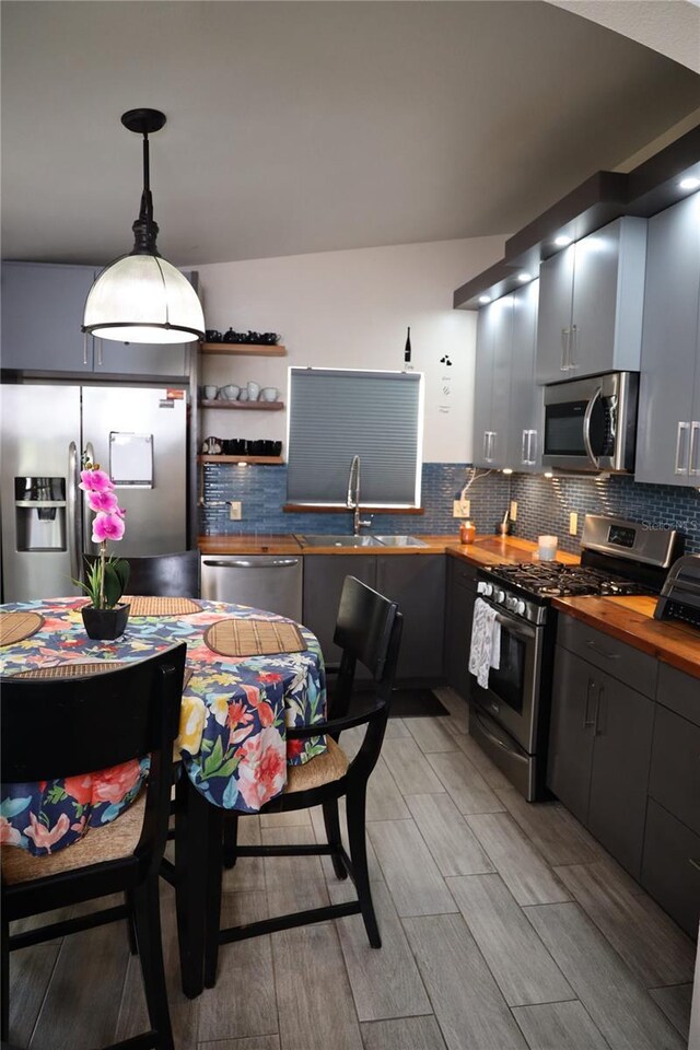 2019 Jaffa Ct, Clermont, FL 34714 - kitchen with appliances with stainless steel finishes, butcher block counters, decorative backsplash, light wood-type flooring, and decorative light fixtures
