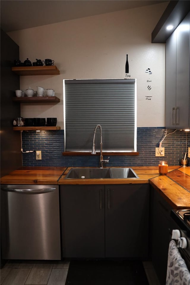 kitchen featuring dishwasher, vaulted ceiling, butcher block counters, sink, and tasteful backsplash