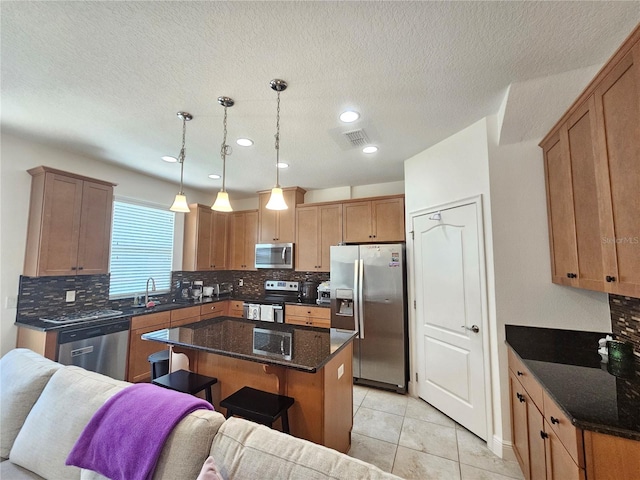 kitchen with dark stone counters, a kitchen island, stainless steel appliances, and backsplash