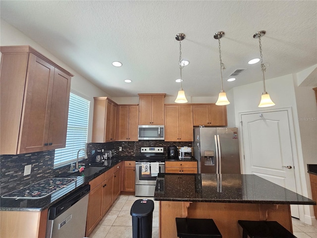 kitchen featuring a kitchen island, sink, decorative backsplash, appliances with stainless steel finishes, and light tile patterned flooring