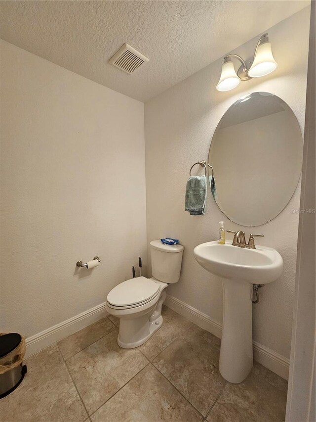 bathroom featuring a textured ceiling, toilet, and tile patterned floors