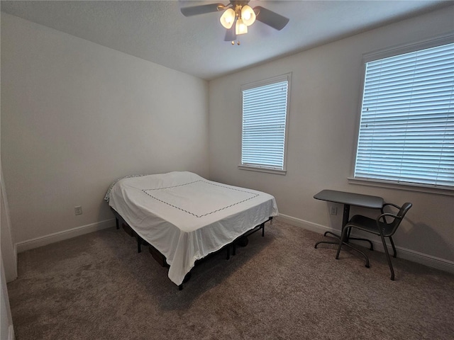 bedroom featuring ceiling fan, dark colored carpet, and multiple windows