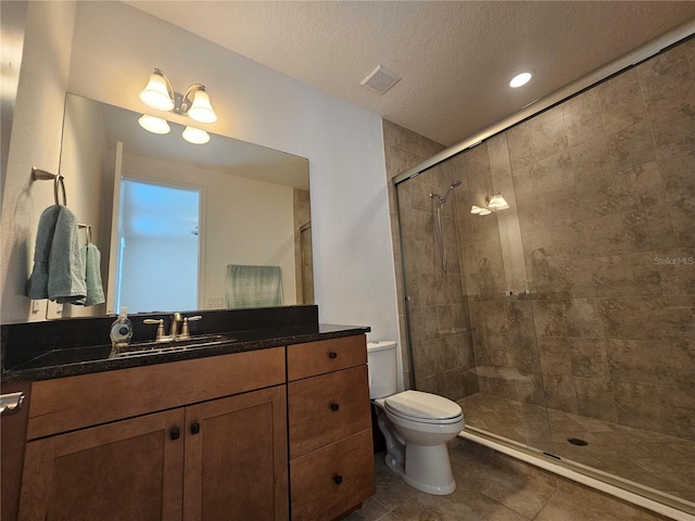 bathroom featuring a textured ceiling, tile patterned floors, walk in shower, toilet, and vanity