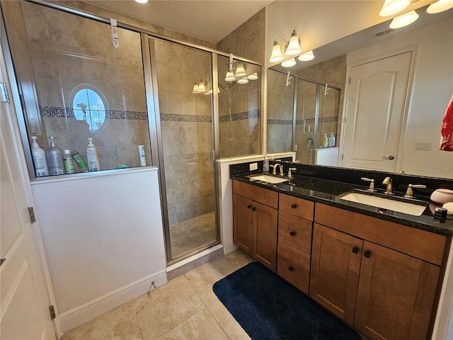 bathroom with a shower with door, vanity, and tile patterned flooring