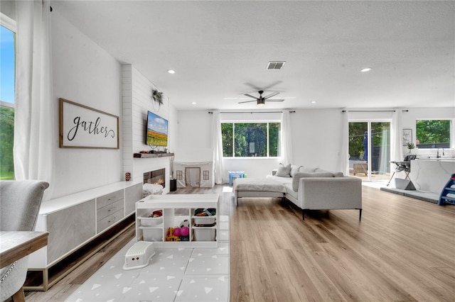 living room featuring a textured ceiling, ceiling fan, and light hardwood / wood-style floors