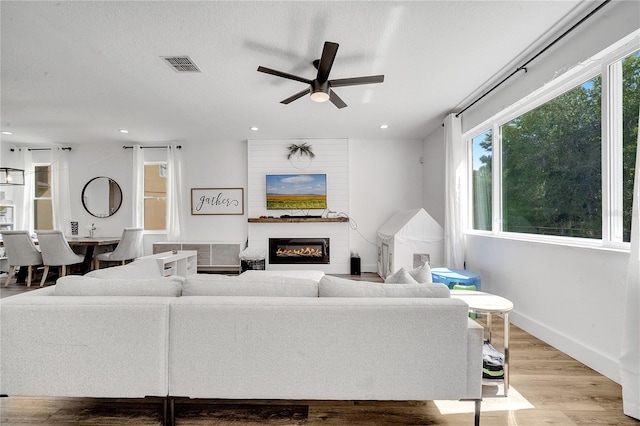 living room featuring a textured ceiling, ceiling fan, and wood-type flooring