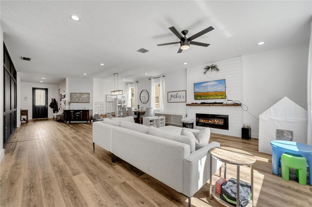 living room featuring ceiling fan, a fireplace, and light hardwood / wood-style flooring